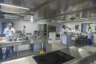 Groupe d'étudiantes en Diététique dans la cuisine pédagogique de l'IUT, préparant des plats sur les paillasses en inox.